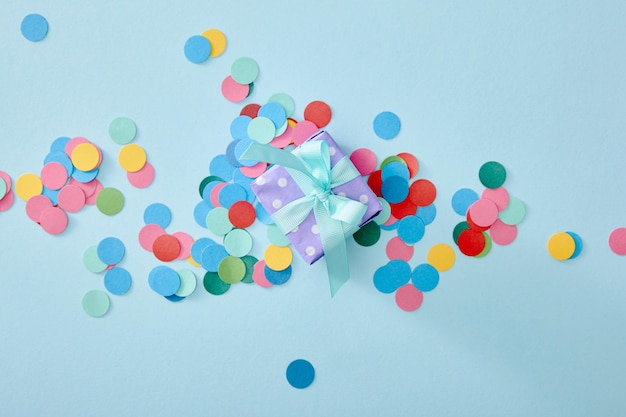 Top view of colorful confetti near present on blue background