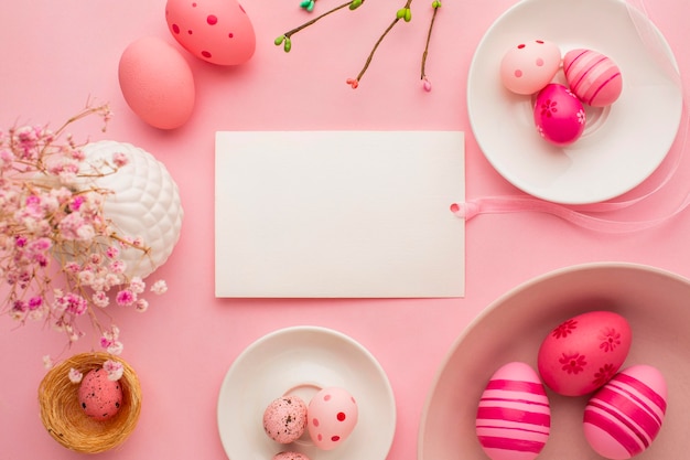 Top view of colorful easter eggs on plates with paper and flowers