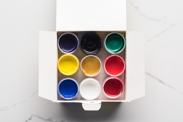 Top view of colorful gouache paints in box on marble surface