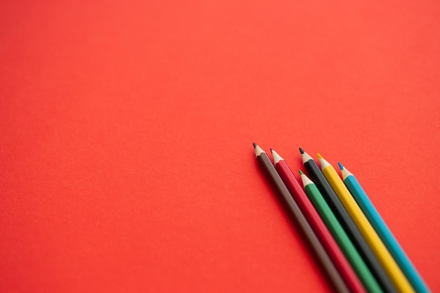 Top view of colorful pencils on red background