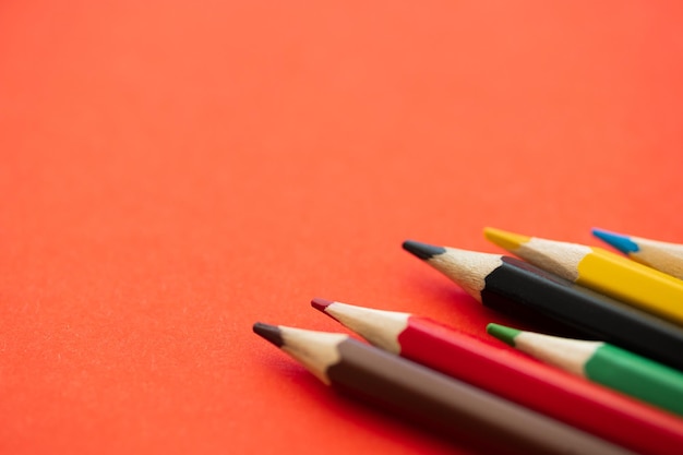 Top view of colorful pencils on red background