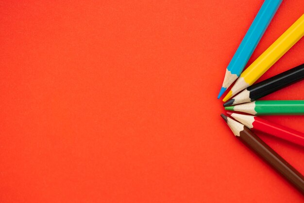 Top view of colorful pencils on red background