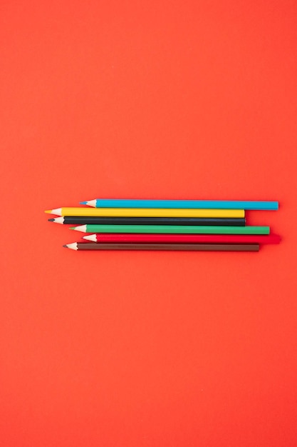 Вид сверху на цветные карандаши на красном фоне