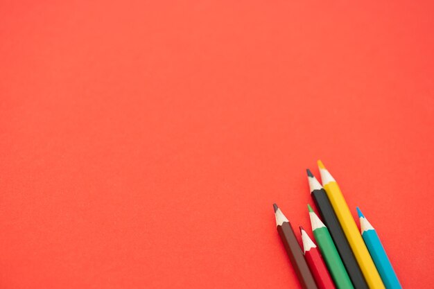 Top view of colorful pencils on red background