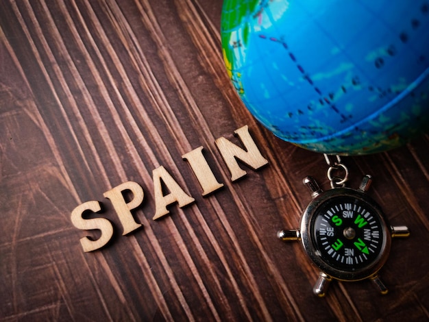 Top view compassearth globe and wooden word with text spain on\
wooden background