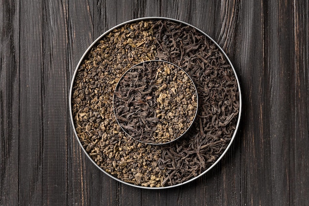 Top view composition of black and green tea on a wooden background