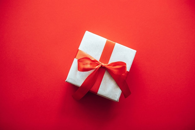 Top view composition of christmas gift box wrapped in craft paper with red ribbon bow