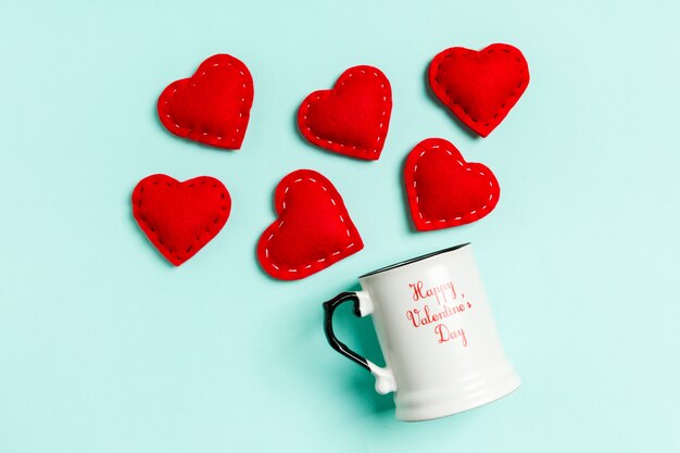 Photo top view composition of red hearts falling out from a cup