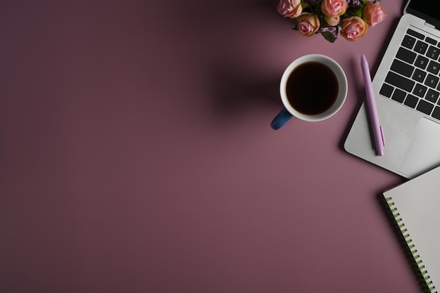 Top view computer laptop notebook and coffee cup on purple background with copy space