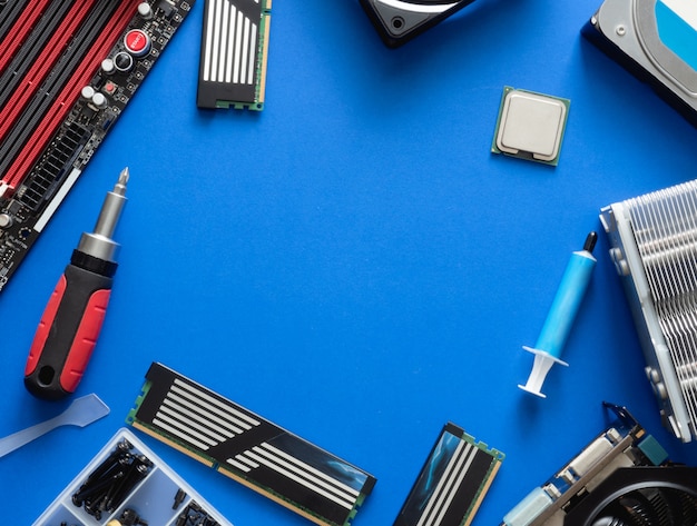 top view of computer parts with harddisk, ram, CPU, graphics card, and motherboard on blue table background.