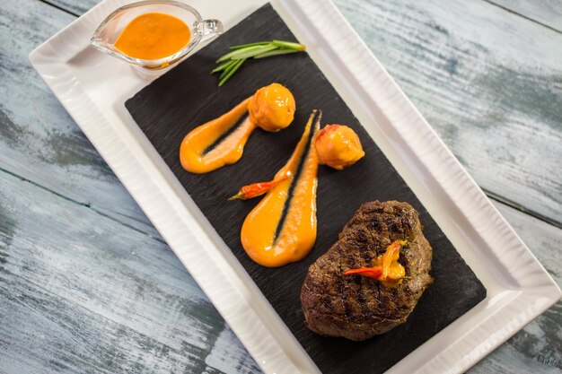 Vista dall'alto di carne cotta. salsa di erbe verdi e arancia. bistecca al pepe servita al caffè. buon appetito.