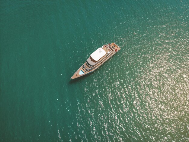 Top view of the cool yacht sailing the Andaman sea, wooden deck, poll, equipment and the turquoise water around; wealth concept.