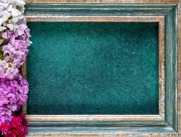 Photo top view copy space greengold frame with pink red and white flowers from the side on a green background