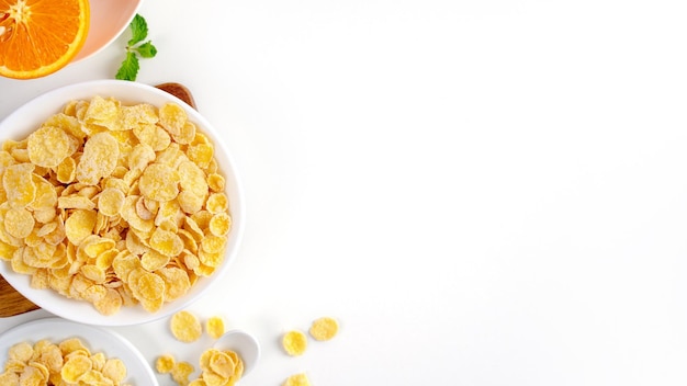 Top view of corn flakes bowl with milk on white background