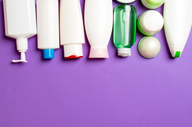 Top view of cosmetics bottles on colored surface