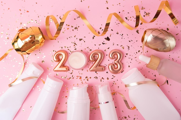 Vista dall'alto dei contenitori per cosmetici su sfondo rosa numeri in oro rosa 2023 sopra