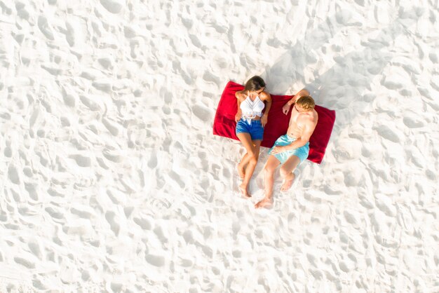 Top view of couple lying on white sand beach 