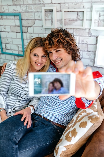 Top view of couple taking selfie on a sofa in a coffee shop Selective focus on couple in background