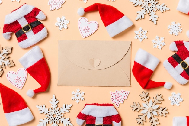 Top view of craft envelope with Christmas decorations and Santa hats on orange background Happy holiday concept