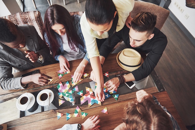 Top view creative photo of friends sitting at wooden table. Friends having fun while playing board game