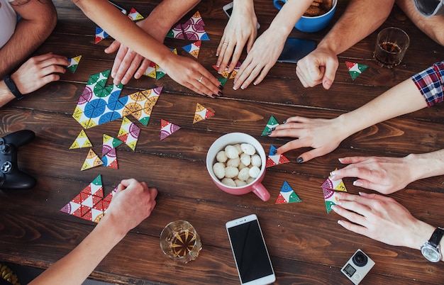 Photo top view creative photo of friends sitting at wooden table.  having fun while playing board game