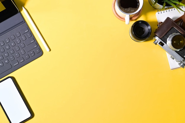 Top view creative yellow  desk with photographer supplies and copy space