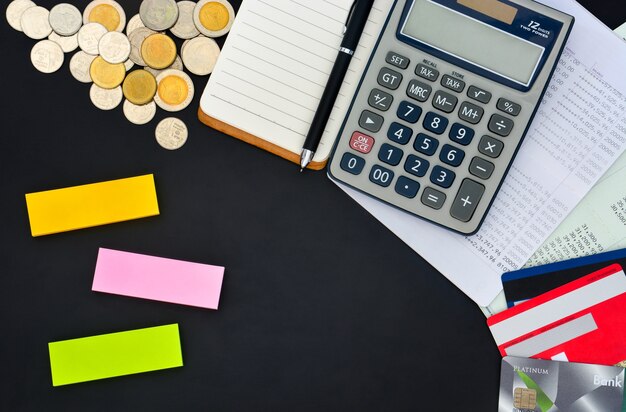 top view of credit cards passbooks calculator notebook pen pile of coins and sticky notes