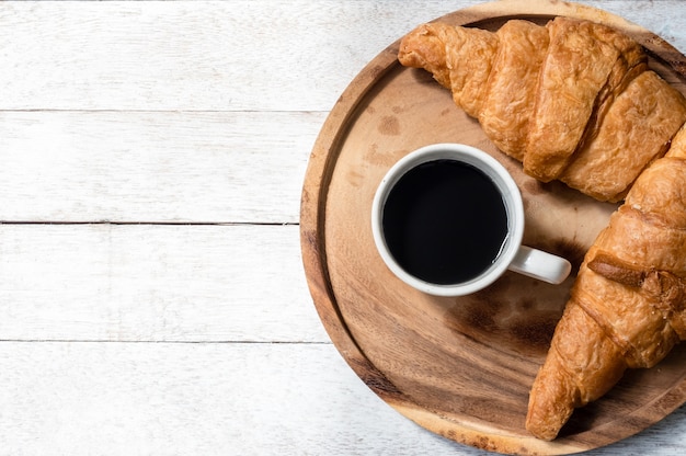 Top view of croissants and coffee on wooden table background. Free space for text