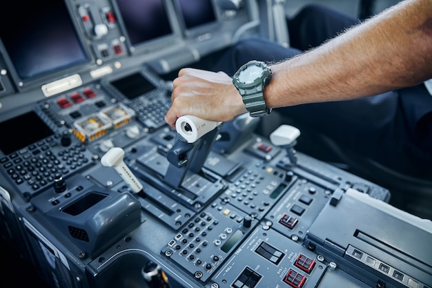 Top view cropped head close up of airman hand swithing level on control in cockpit during flight