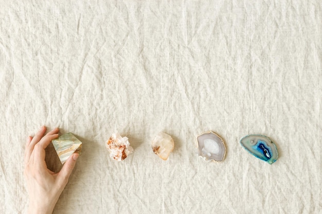 Top view crystal and stone in row female hand hold one of healing minerals agate quartz amethyst