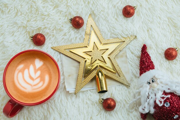 Top view cup cappuccino and Santa Claus toy on a of fluffy white blanket