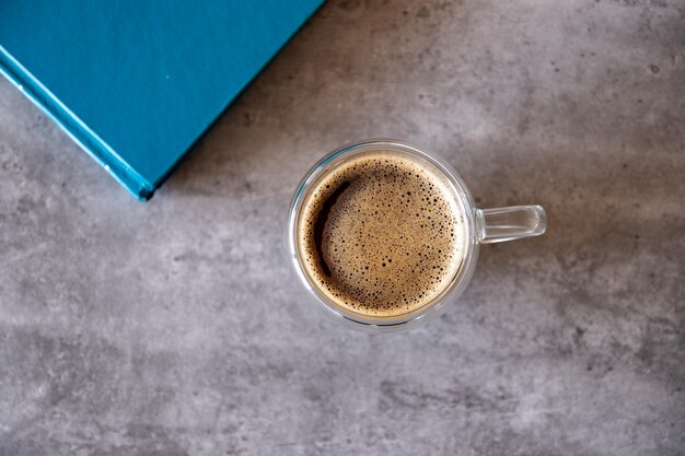 Top view for cup of coffee on grey background and book