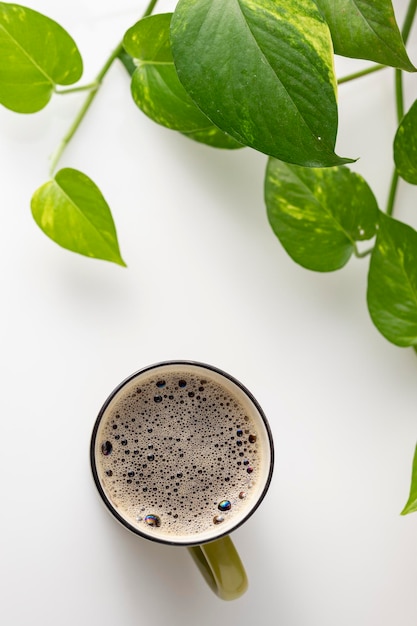 Top view of a cup of coffee next to some vines and copy space