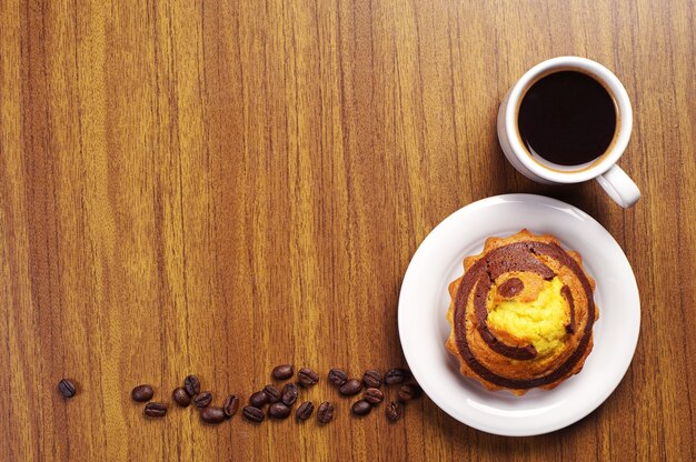 一杯のコーヒーと机の上にチョコレートと甘いカップケーキの上面図