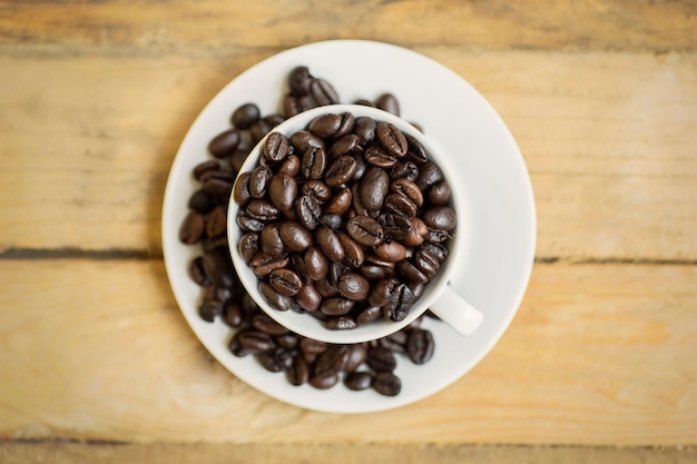 Top view of a cup full of coffee beans on the saucer over wooden table shot in 4k resolution