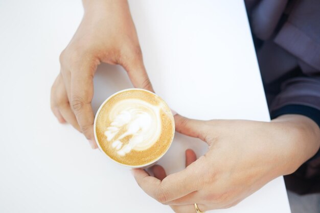 Top view of a cup of late coffee with heart shape design on top on cafe table