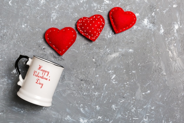 Top view of a cup and red hearts falling out from it