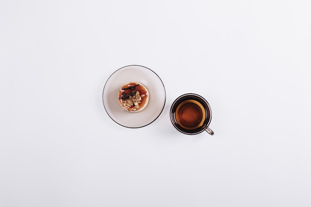 Top view of a cup of tea and cake on the saucer on table