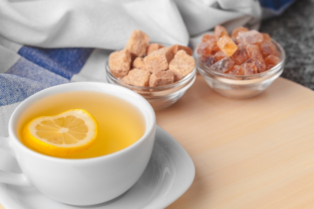 Top view of a cup of tea with lemon piece on wooden table