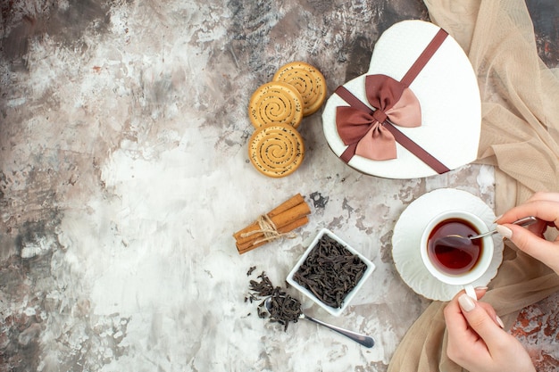 Vista dall'alto tazza di tè con biscotti dolci e presente sullo sfondo chiaro coppia di san valentino sensazione di colore zucchero amore matrimonio biscotto