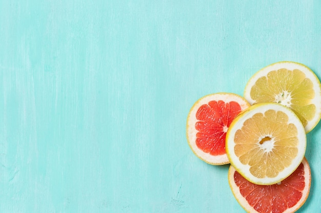 Top view on cut red and yellow grapefruit on a turquoise wooden background