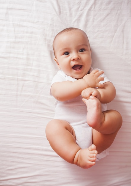 Top view of a cute baby lying on a bed with raised feet up