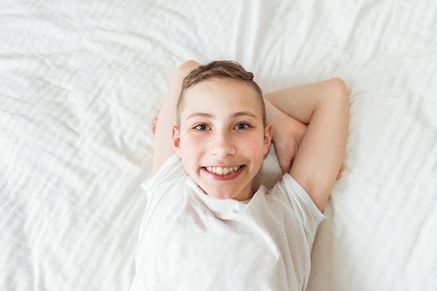 Top view of cute dreaming boy lying with comfortable on bed