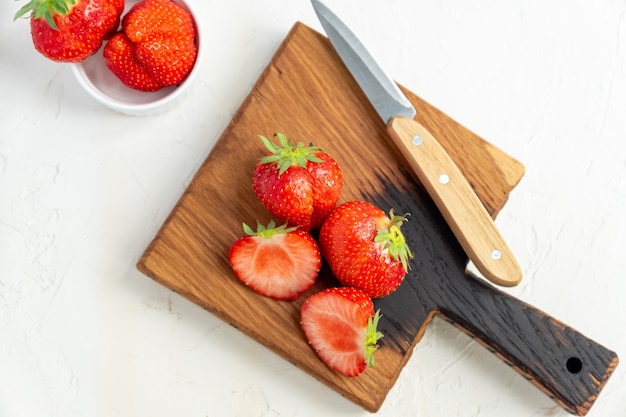 Top view of cutting desk with fresh ripe strawberry on white table