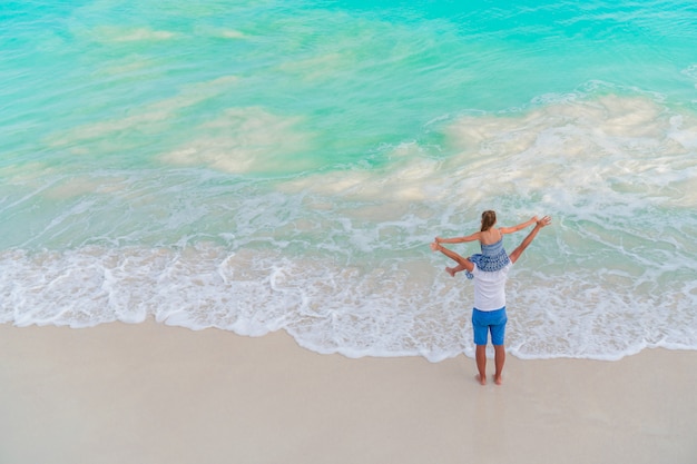 Top view of dad and little kid at tropical beach with turquoise water