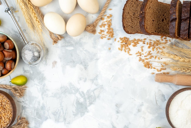 Top view dark bread with nuts flour eggs and milk on a white background photo color cake pie hotcake bun biscuit dough