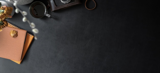 Top view of dark trendy workplace with copy space and office supplies on black leather desk 