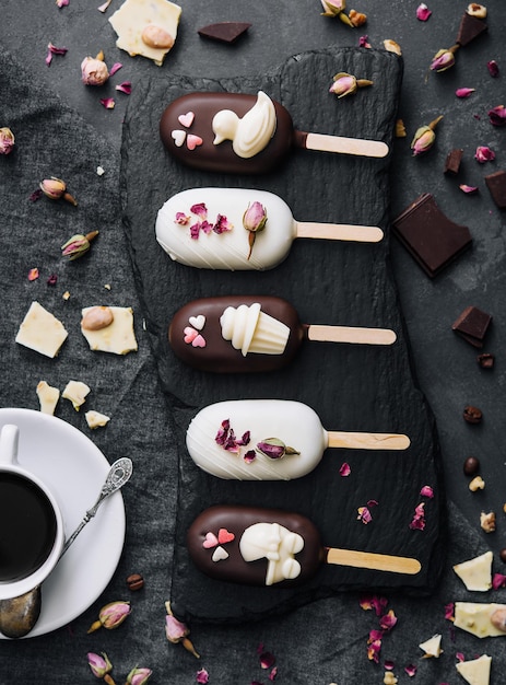 Top view of decorated cake pops ice creams on black background