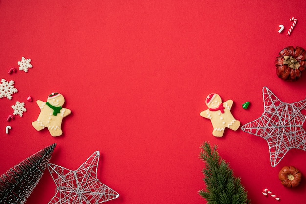 Top view of decorated Christmas gingerbread cookies with decorations on red table background with copy space, concept of holiday celebration.