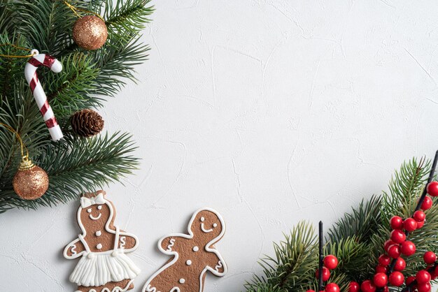 Top view of decorated Christmas gingerbread cookies with decorations on white table background with copy space, concept of holiday celebration.